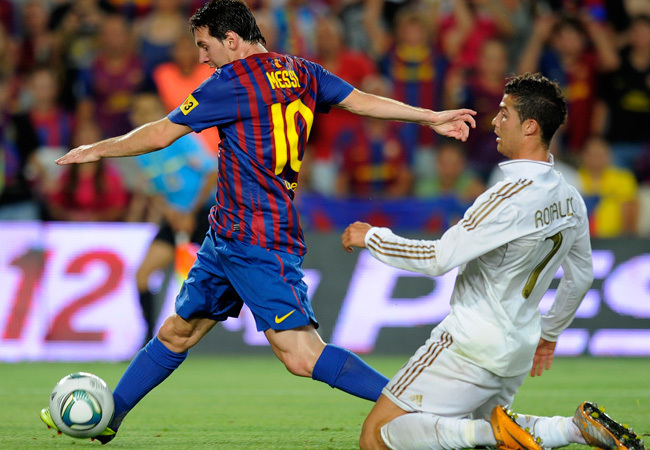 Lionel Messi lő gólt Cristiano Ronaldo mellett a Barcelona-Real Madrid mérkőzésen, a spanyol Szuperkupa visszavágóján a Nou Campban 2011 augusztusában