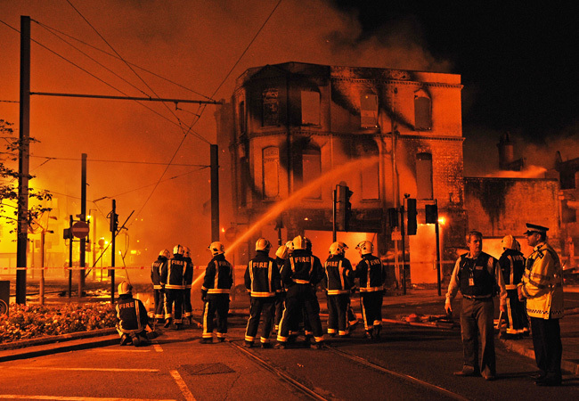 Londoni tűzoltók oltanak egy égő épületet, amit zavargók felgyújtottak 2011 augusztusában