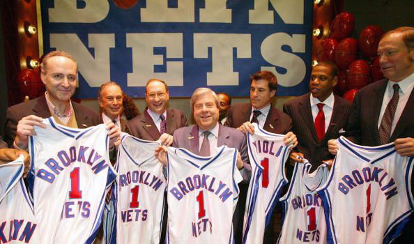 A New Jersey Nets tulajdonosai állnak Brooklyn Nets feliratú mezekkel, miután bejelentették, hogy átnevezik és elköltöztetik a csapatot 2011 szeptemberében