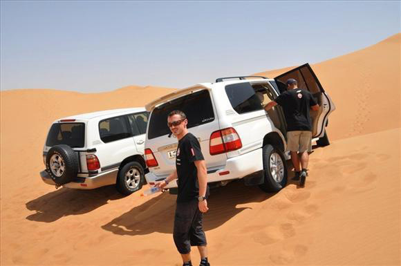 Adam Malysz, korábbi lengyel síugró sétál két Land Rover terepjáró mellett a sivatagban az Egyesült Arab Emirátusokban, ahol a Dakar rali nevű terepraliversenyre készül 2011 augusztusában