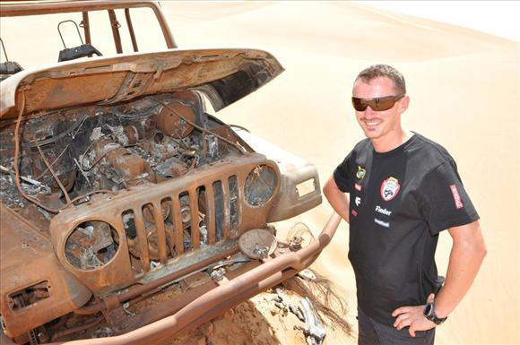 Adam Malysz, korábbi lengyel síugró áll egy terepjáró roncsa mellett a sivatagban az Egyesült Arab Emirátusokban, ahol a Dakar rali nevű terepraliversenyre készül 2011 augusztusában