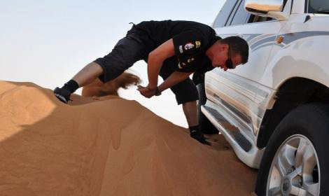 Adam Malysz, korábbi lengyel síugró ássa ki egy autó kerekét a homokból a sivatagban az Egyesült Arab Emirátusokban, ahol a Dakar rali nevű terepraliversenyre készül 2011 augusztusában