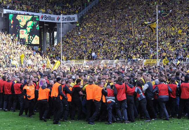 A Dortmund szurkolóit próbálják visszatartani a biztonságiak a csapat bajnoki címe után a Signal Iduna Parkban 2011 májusában