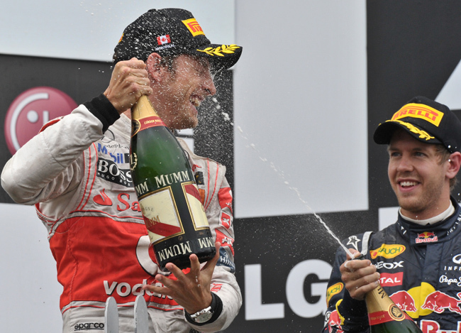 Button pezsgőzik Vettellel a Kanadai Nagydíj eredményhirdetésekor - Fotó: AFP