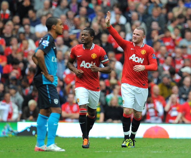 Wayne Rooney és Patrice Evra ünneplik a Manchester United egyik gólját Theo Walcott mellett az Arsenal ellen az Old Trafford stadionban 2011 augusztusában