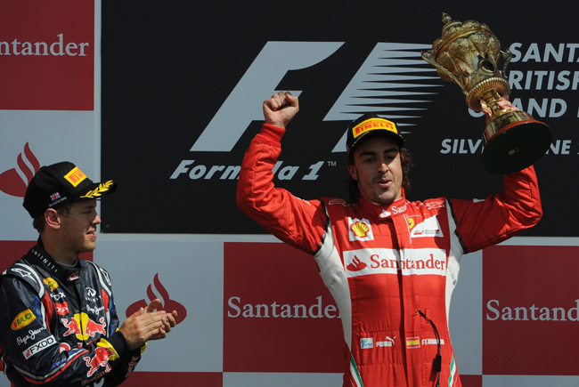 Fernando Alonso ünnepli első helyét a Brit Nagydíjon, a második Sebastian Vettel megtapsolja. 