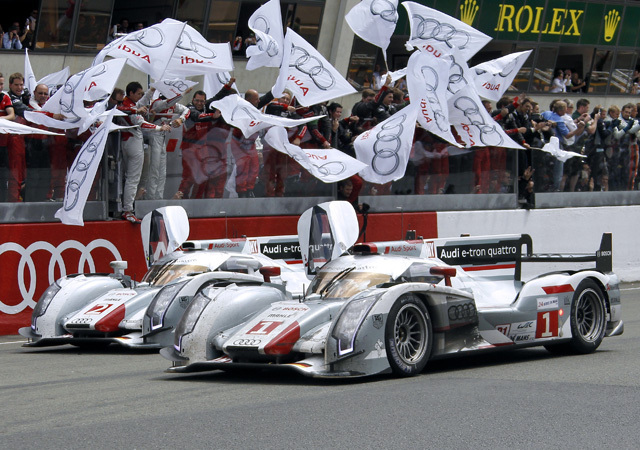 Andre Lotterer és Tom Kristensen vezetik az Audi R18-as versenyautóit a Le Mans-i 24 órás verseny céljában 2012-ben.