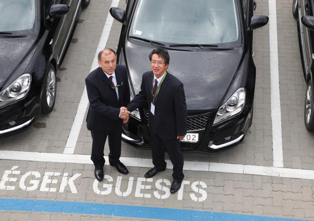 Molnár Zoltán, a Magyar Olimpiai Bizottság főtitkára, és Hisashi Takeuchi, a Magyar Suzuki Zrt. vezérigazgatója fognak kezet, amikor a Suzuki, a MOB gyémánt fokozatú főtámogatója átadja az olimpikonoknak új autóikat 2011 októberében