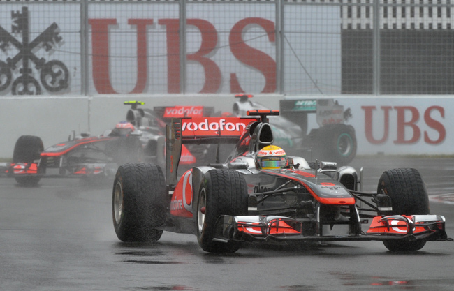 Lewis Hamilton vezeti McLaren Mercedesét csapattársa, Jenson Button előtt a Forma-1 egyik nagydíján 2011-ben